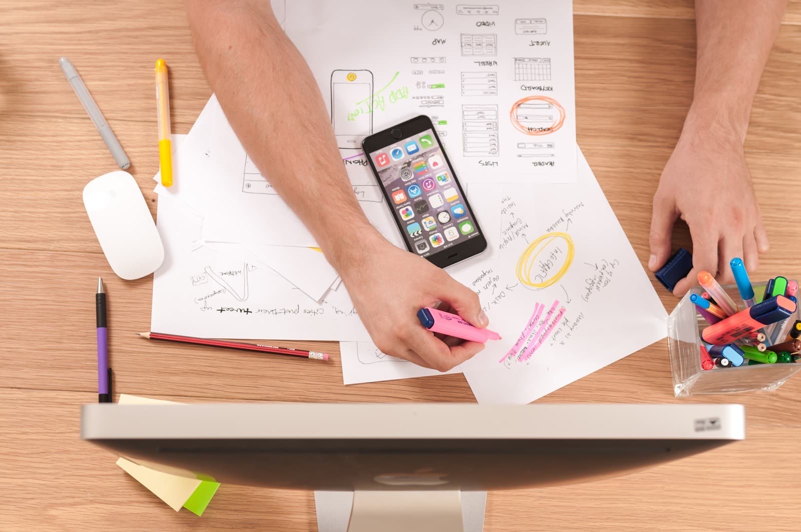 A working session with interface sketches, a phone, and a desktop computer